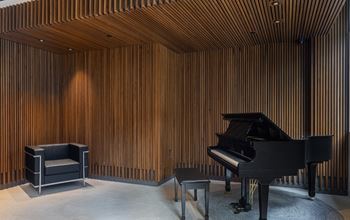 a living room with a piano and a wooden wall